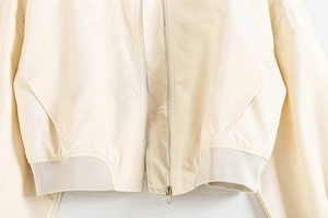 Détail d'un blouson aviateur Y2K crème avec fermeture éclair en métal et ourlet côtelé