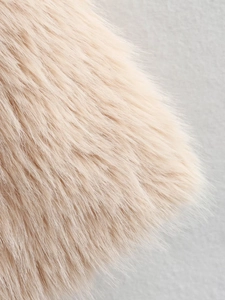 Vue macro d'une texture en fausse fourrure rose clair montrant la matière douce et brillante
