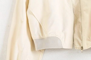 Détail du blouson bomber beige avec fermeture éclair argentée et l'ourlet en maille côtelée