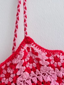 Detailed close-up of pink and red crochet floral patterns and braided shoulder straps