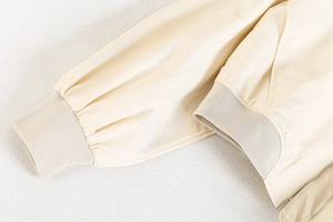 Détail rapproché des poignets et de l'ourlet côtelés sur un blouson court crème Y2K