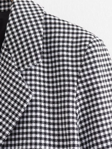 Détail macro du revers de blazer à motif pied-de-poule et texture tissée