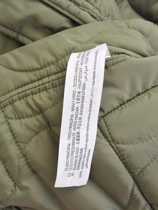 Macro detail of the product wash care label on olive green quilted cotton jacket
