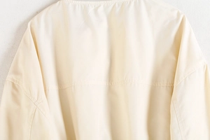 Gros plan détaillé de la double couture sur le blouson bomber beige style y2k