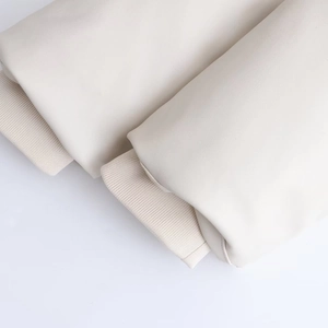 Détail de la manche en similicuir crème avec poignets en maille côtelée coupe-vent