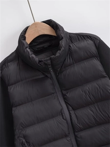 Nahaufnahme der schwarzen Steppjacke mit Stehkragen und Ärmeln im Materialmix-Design