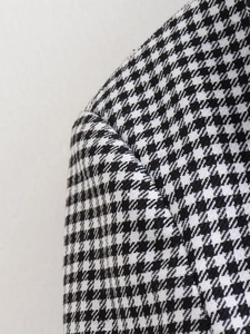 Détail de la texture du tissu pied-de-poule noir et blanc sur l'épaule de la veste y2k