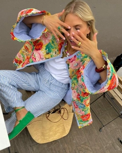 Veste matelassée fleurie et pantalon rayé élégants dans un décor urbain extérieur