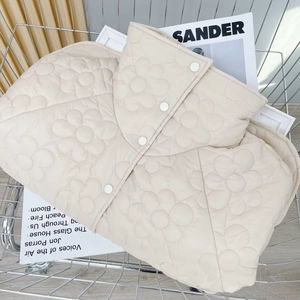 Detail der cremefarbenen Steppjacke mit 3D-Blumenzier und Stehkragen im Metallkorb