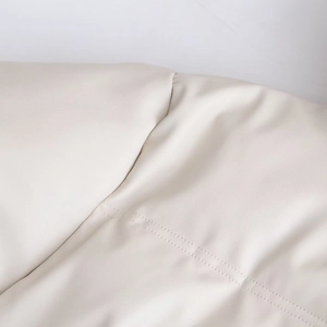 Détail du tissu en similicuir crème avec des finitions de double couture de qualité