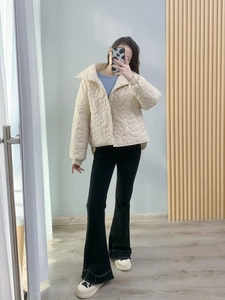 Detail der beigen Steppjacke mit Blumenmuster und schwarzer Schlaghose