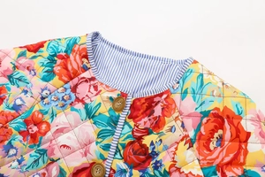 Détail d'une veste matelassée à fleurs avec motifs de roses et boutons en bois