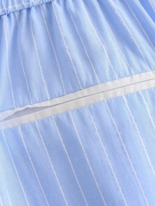 Close-up of blue and white striped cotton fabric with elastic pleats and white piping detail