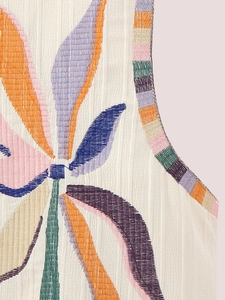 Macro detail of bohemian crinkle fabric with vibrant multi-color leaf embroidery on vest