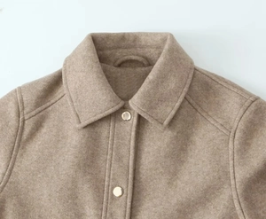 Detail of soft tweed jacket showing classic collar and gold snap buttons on brown fabric