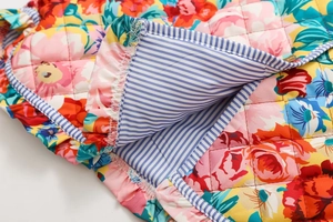 Gros plan sur tissu matelassé à fleurs avec doublure à rayures bleues et volant