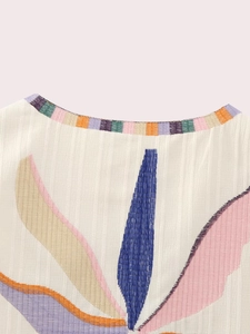 Detail of round neckline with rainbow trim and colorful leaf embroidery on vest
