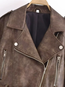 Detailed macro view of vintage brown faux leather jacket with silver studs and zippers