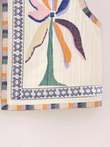 Macro view of detailed colorful palm tree embroidery on a beige textured vest