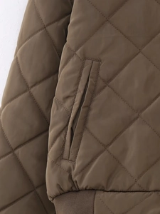 Detailed close-up of brown quilted jacket showing diamond pattern and ribbed hem