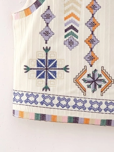 Close-up of colorful ethnic geometric embroidery on white sleeveless vest top