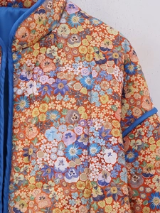 Détail macro de la veste matelassée Y2K avec imprimé floral et liseré en satin bleu