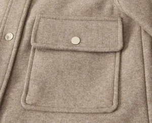 Detailed macro view of the wool-like fabric texture and golden metal buttons on the pocket
