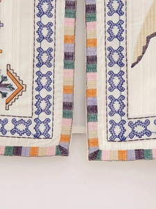 Detailed close-up of ethnic geometric embroidery and cotton linen fabric texture on vest