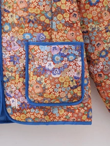 Détail d'une veste matelassée Y2K avec imprimé floral et passepoil bleu sur la poche
