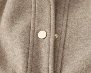 Detail of soft brown wool fabric texture with minimalist light gold metal snap button
