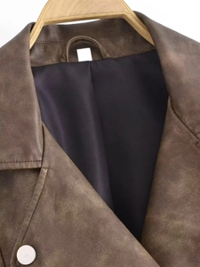 Detailed view of the vintage wash lapel and matte metal button on a brown leather jacket