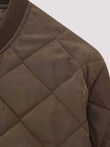 Close-up of diamond quilted pattern and ribbed collar on dark brown puffer jacket