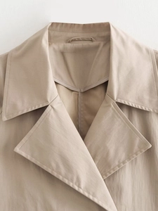 Detailed close-up of double-breasted trench coat lapel collar and clean inner stitching