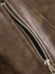 Detail of silver metal zipper and washed vintage brown faux leather texture on jacket