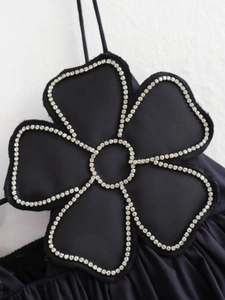Makroaufnahme der 3D-Blumenapplikation mit glitzernden Straßsteinen auf schwarzem Top