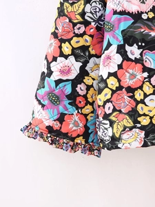 Close-up of floral quilted jacket with colorful flower patterns and ruffled trim detail