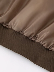 Macro detail of the smooth silk lining and ribbed knit cuff on this brown bomber jacket