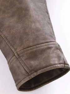 Detailed close-up of vintage brown faux leather jacket sleeve with reinforced double stitching