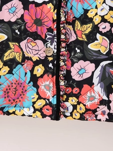 Close-up of diamond quilted jacket with colorful floral prints and a wooden button detail