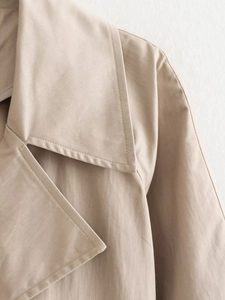 Detailed close-up of khaki trench coat wide lapel showing premium twill fabric texture