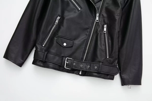 Detailed view of black faux leather motorcycle jacket featuring silver zippers and waist belt