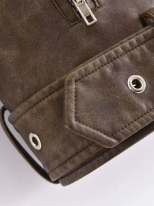Close-up of vintage brown leather jacket featuring metallic zipper and eyelet buckle detail
