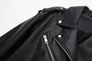 Detail of black faux leather motorcycle jacket featuring silver zippers and shoulder epaulets