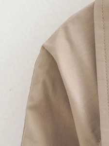 Macro shot of khaki twill fabric texture and fine stitching on a slim-fit trench coat