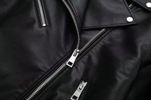 Close-up of black faux leather texture with high-quality silver zippers and metal snaps