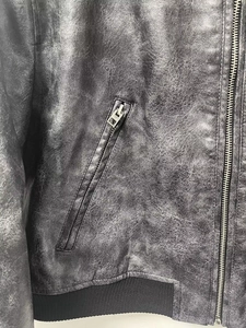 Close-up of vintage black faux leather jacket with metal zippers and ribbed elastic hem