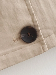 Detailed macro view of high-quality resin buttons on a khaki trench coat fabric