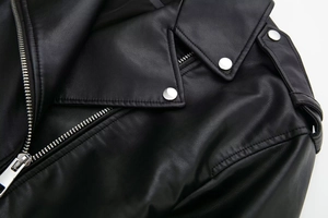 Close-up of black faux leather biker jacket featuring silver zippers and metallic lapel snaps