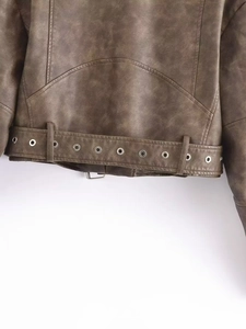 Close-up of vintage faux leather jacket hem with eyelet belt and metal hardware detail