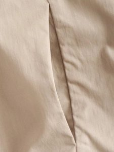 Detailed close-up of beige twill fabric texture and neat stitching on a women trench coat